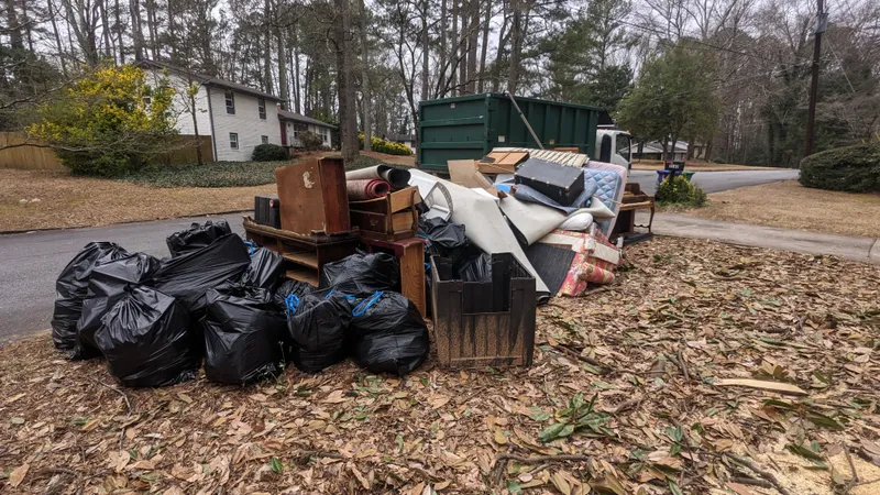 A roll-off container on the truck beside the household load it collected, on a Peachtree Junk Removal job in Decatur